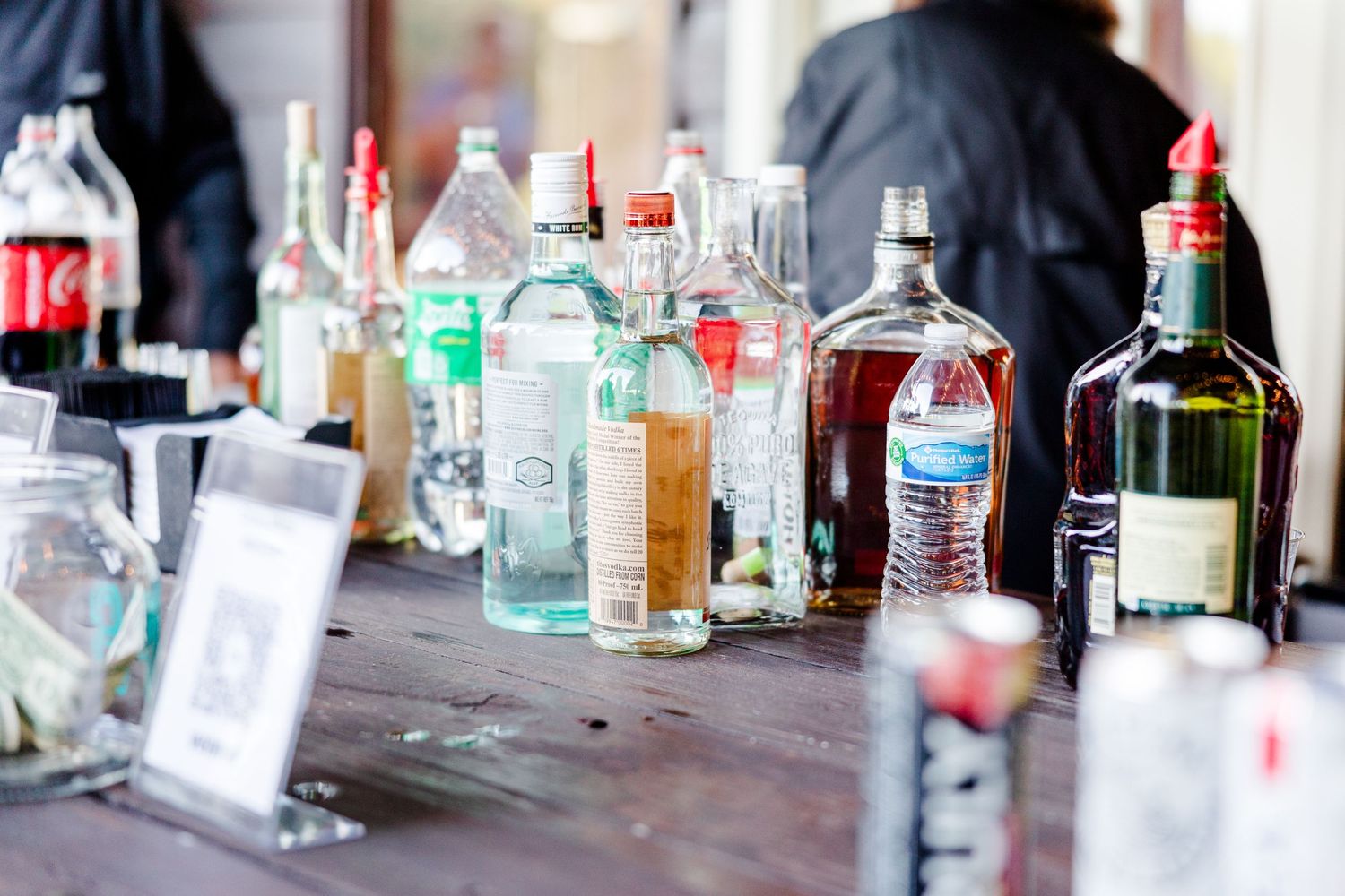 Wedding bar setup with various liquor bottles and mixers arranged on wooden surface.