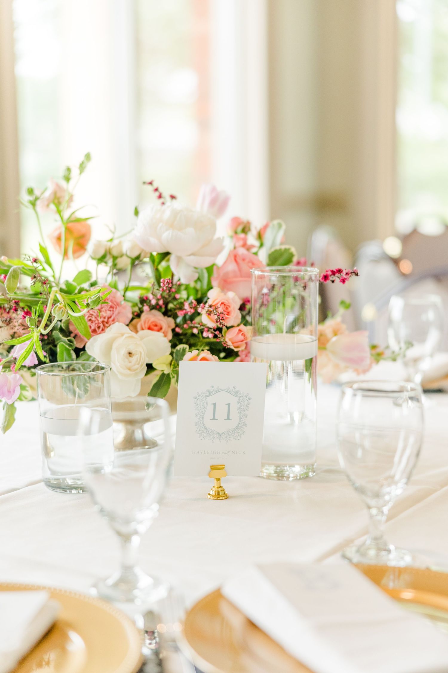 An elegant wedding table setting with pink and white floral centerpieces and crystal glassware.