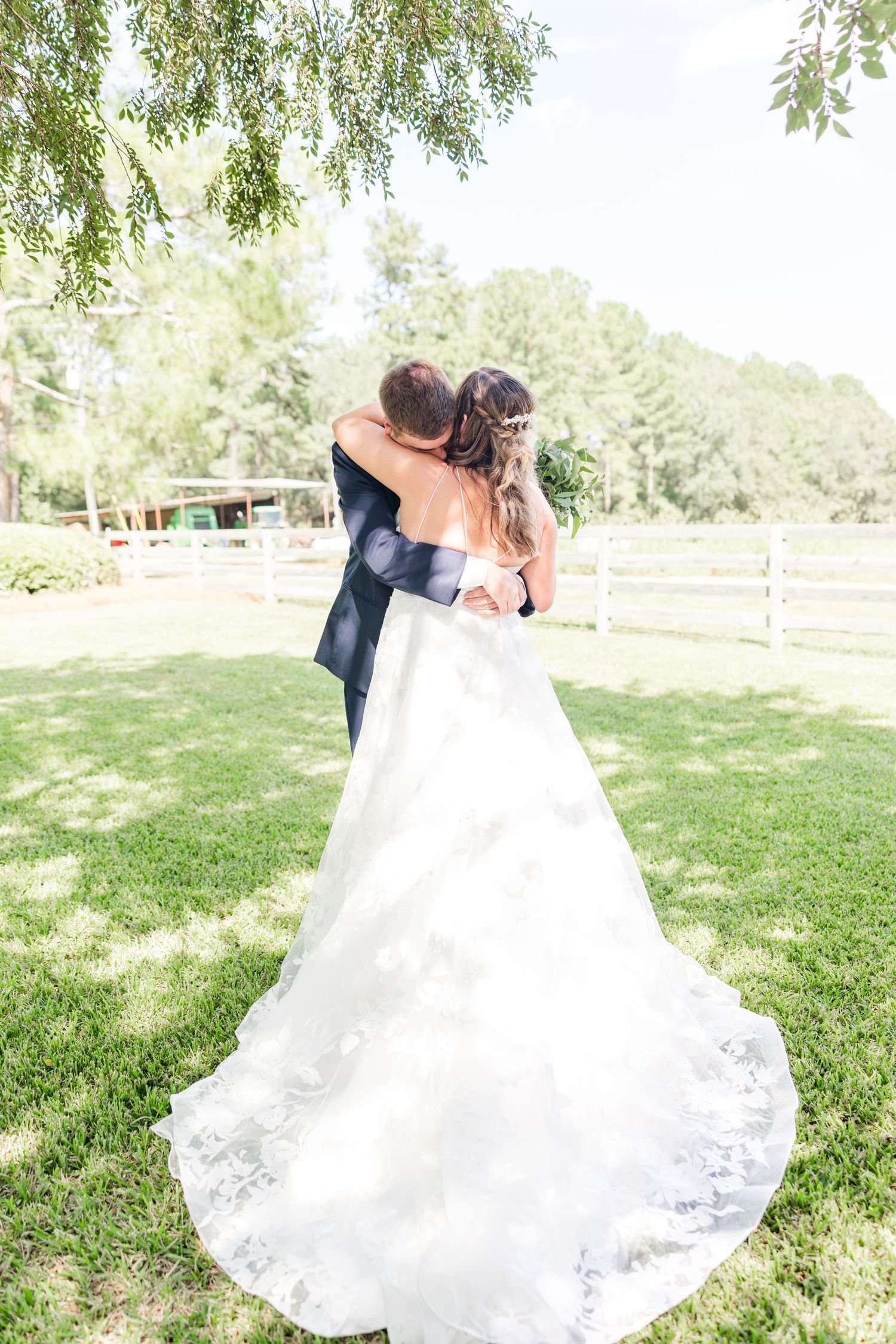 Elegant wedding photography captures couple's romantic dance on sunlit lawn.
