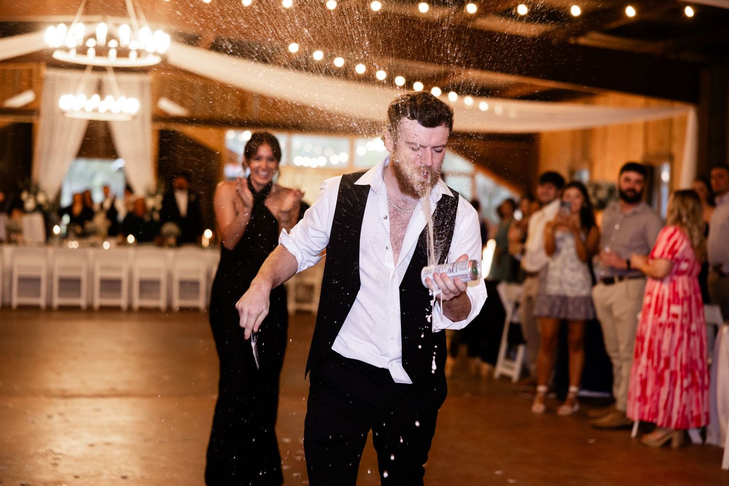 A lively reception scene with dancing and celebration under warm lighting.