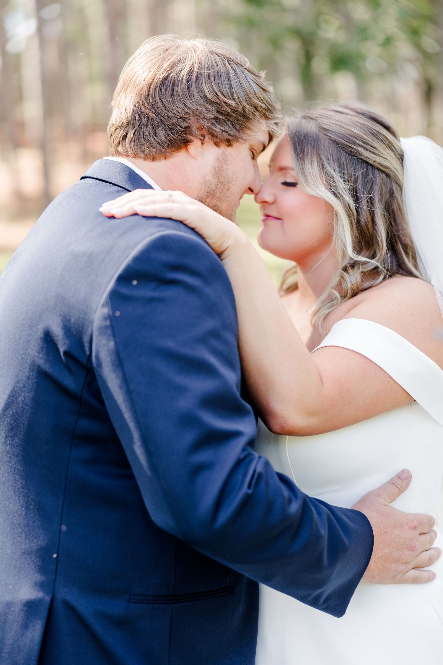 Tender embrace between newlyweds during outdoor wedding photoshoot.