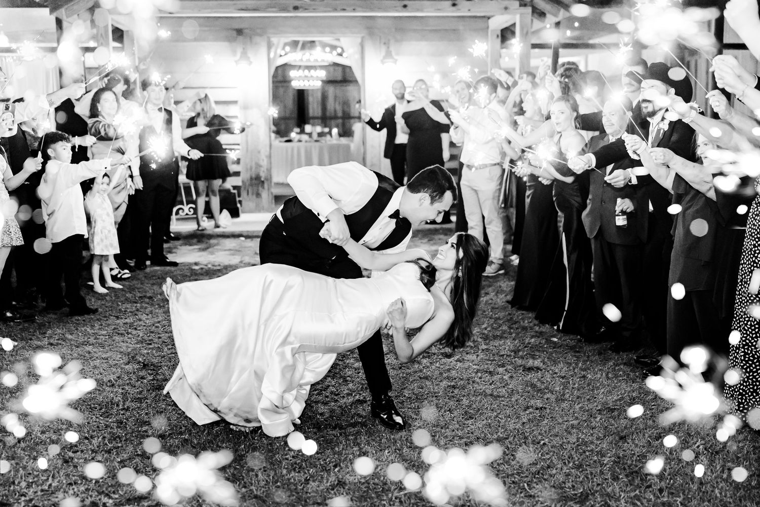 Wedding guests throw white flower petals during an outdoor celebration.