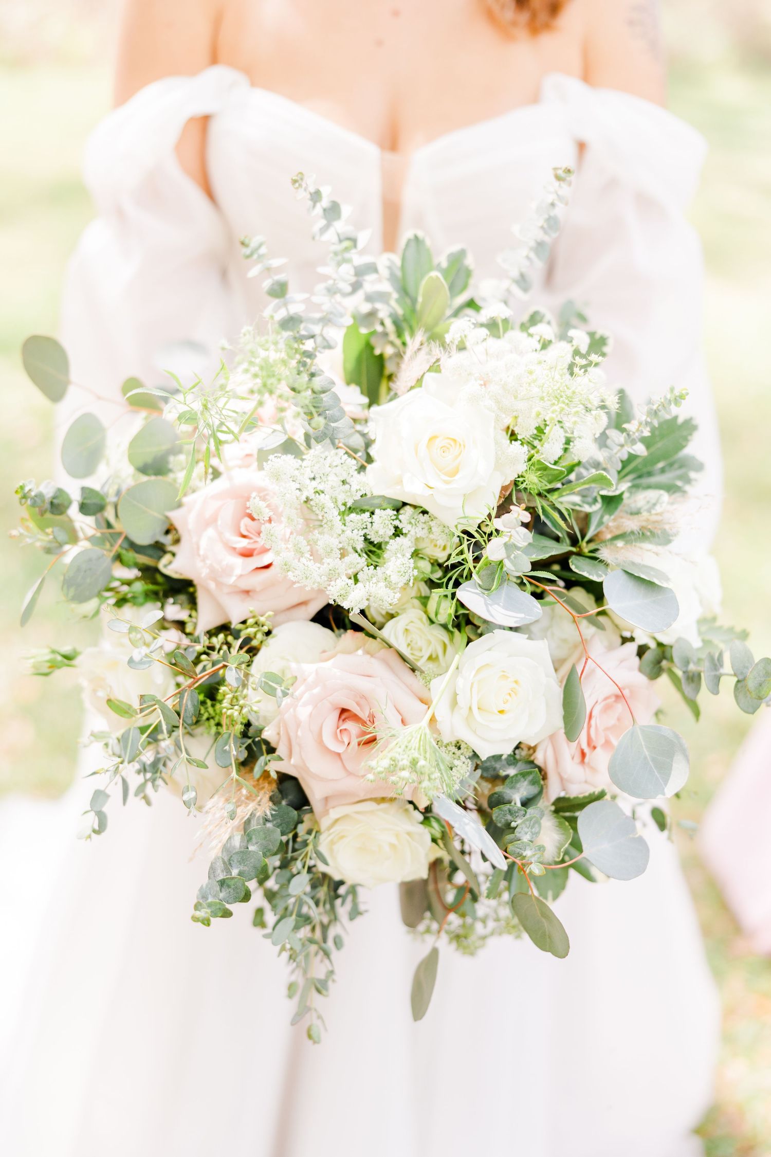 A delicate bridal bouquet featuring blush roses, white flowers, and eucalyptus greenery.