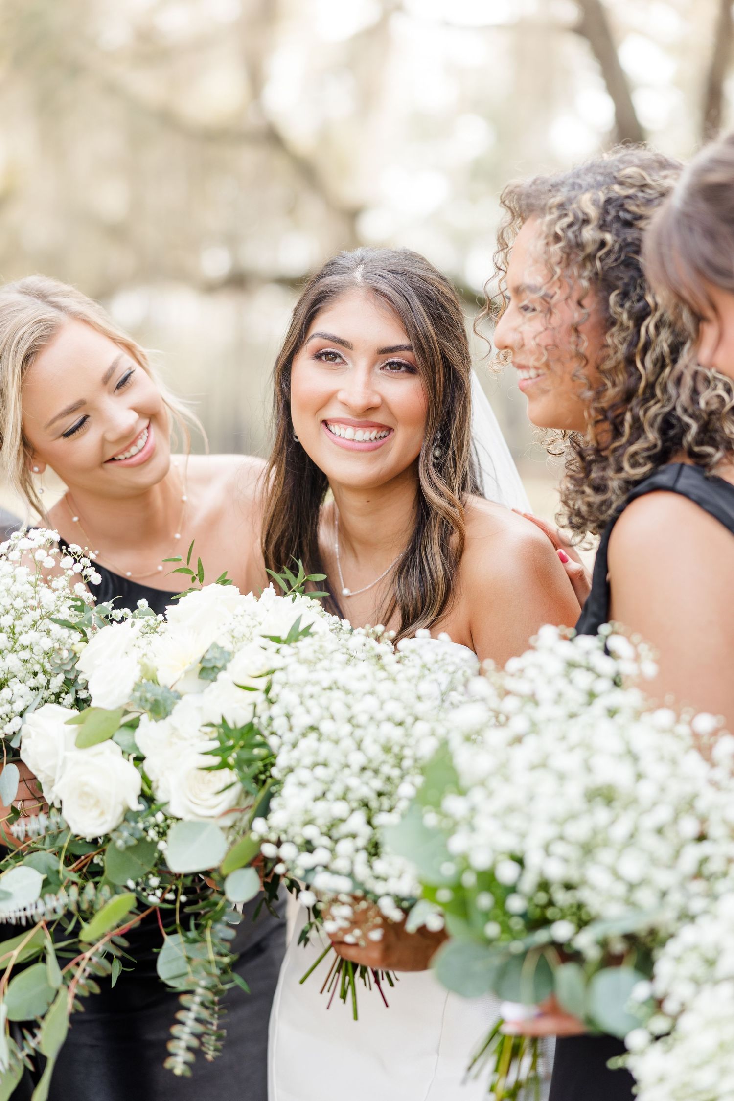 Bridesmaids share joyful moment with their white and green floral bouquets.