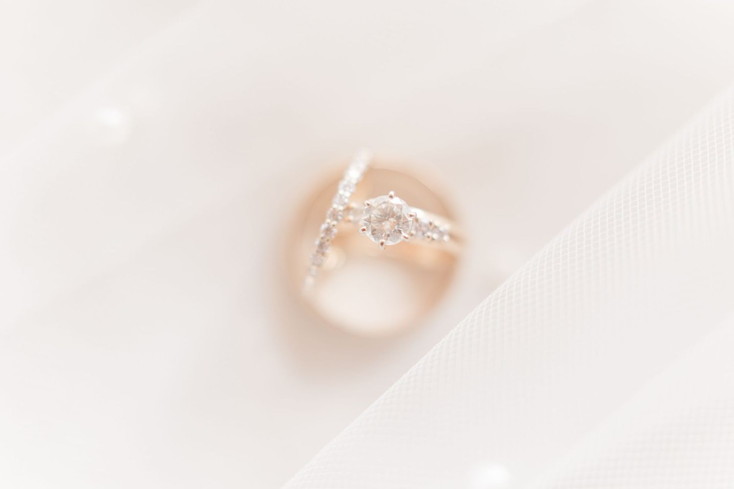 Diamond wedding bands nestled in ethereal white fabric with soft lighting.