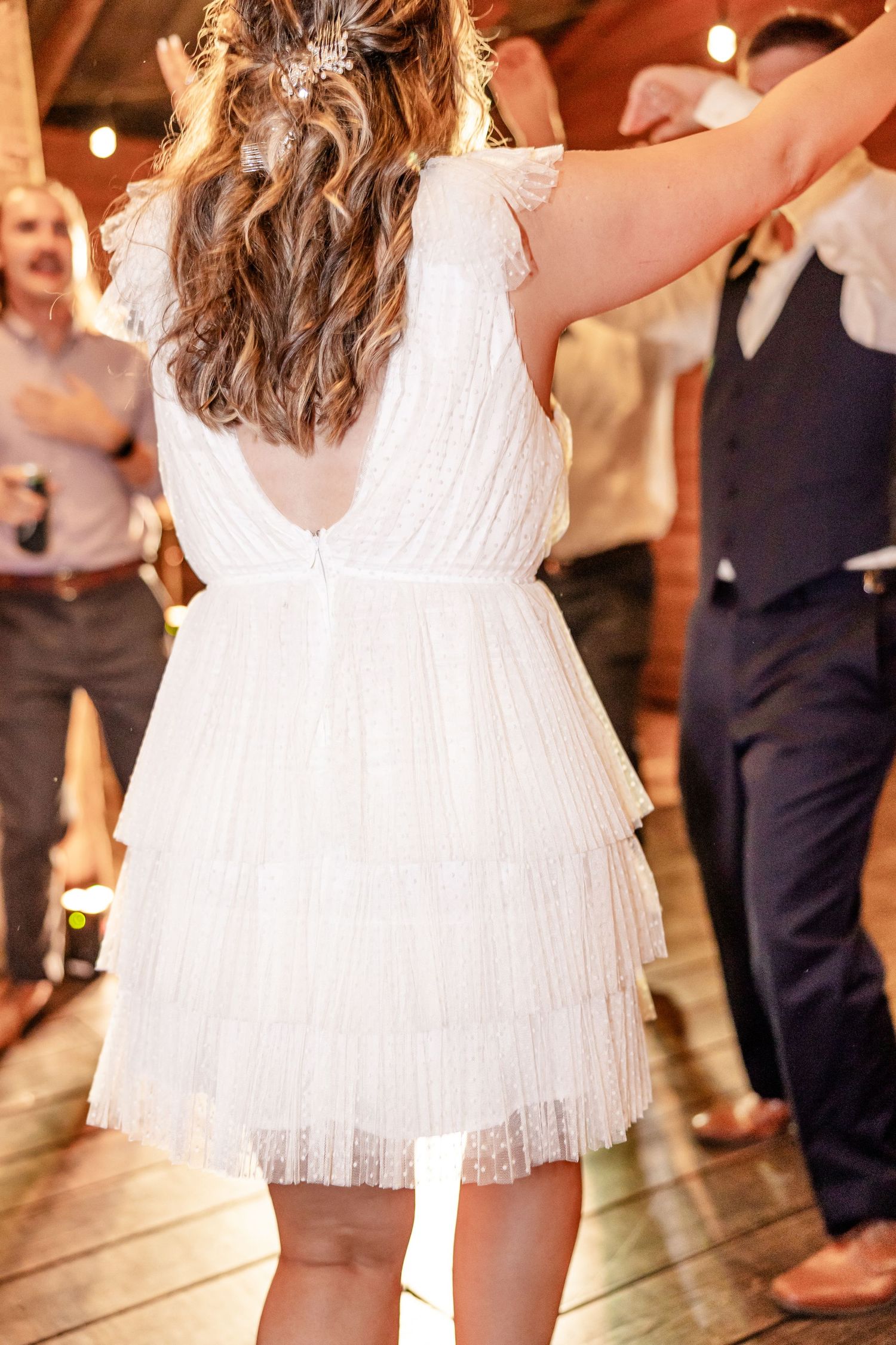 Close-up of a white frilly dress twirling on a dance floor during a celebration.