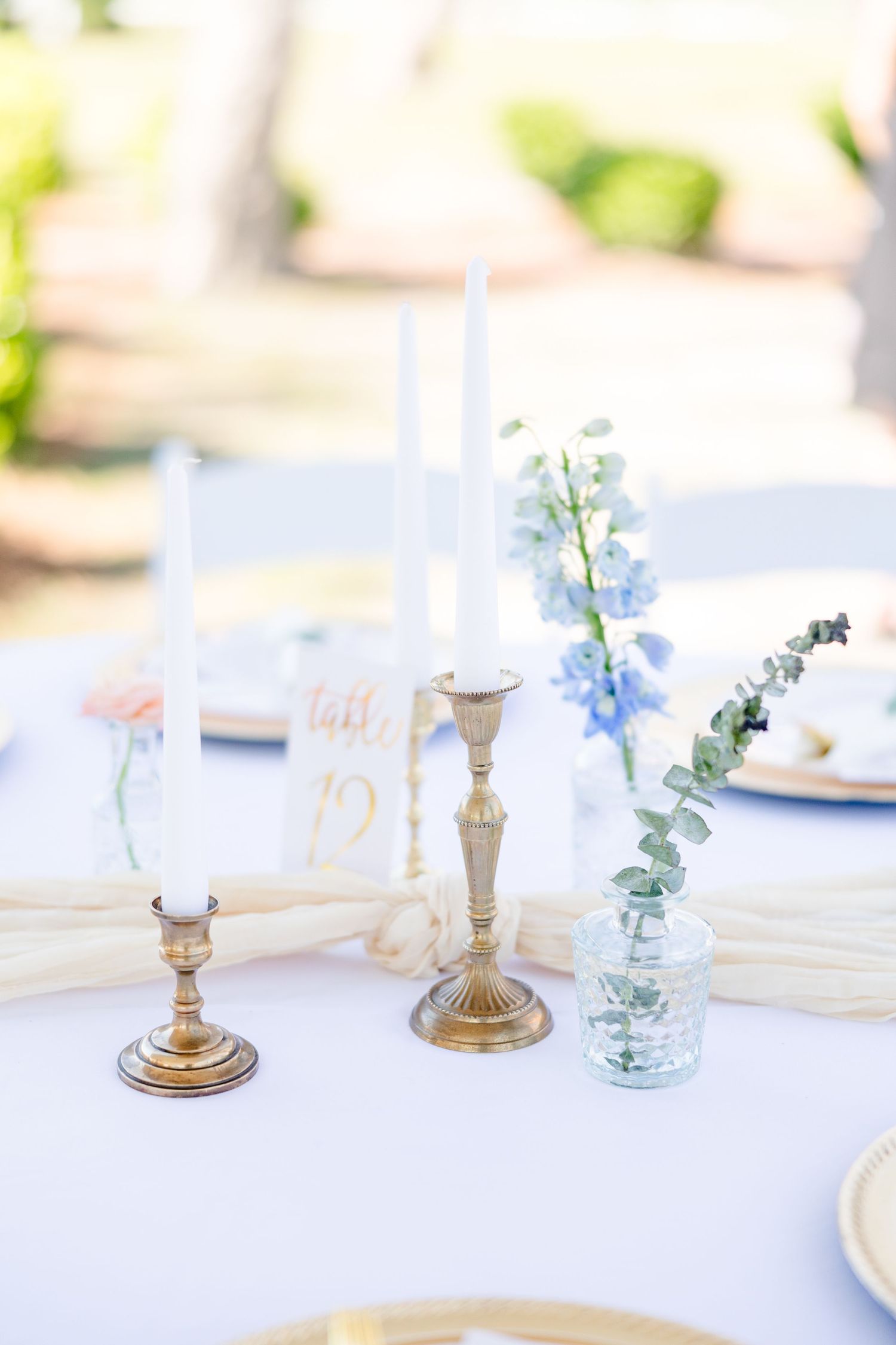 Elegant table setting with gold candlesticks and delicate floral arrangements.