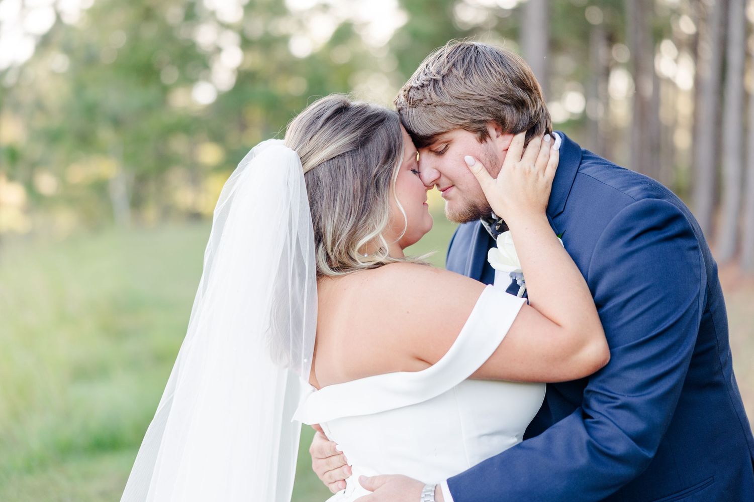 Romantic wedding moment captured under a gazebo with flowing white veil in soft lighting.