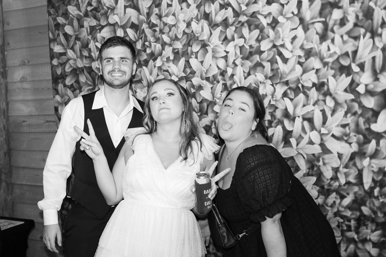 Festive wedding reception scene with decorative leaf pattern backdrop and dancing guests.