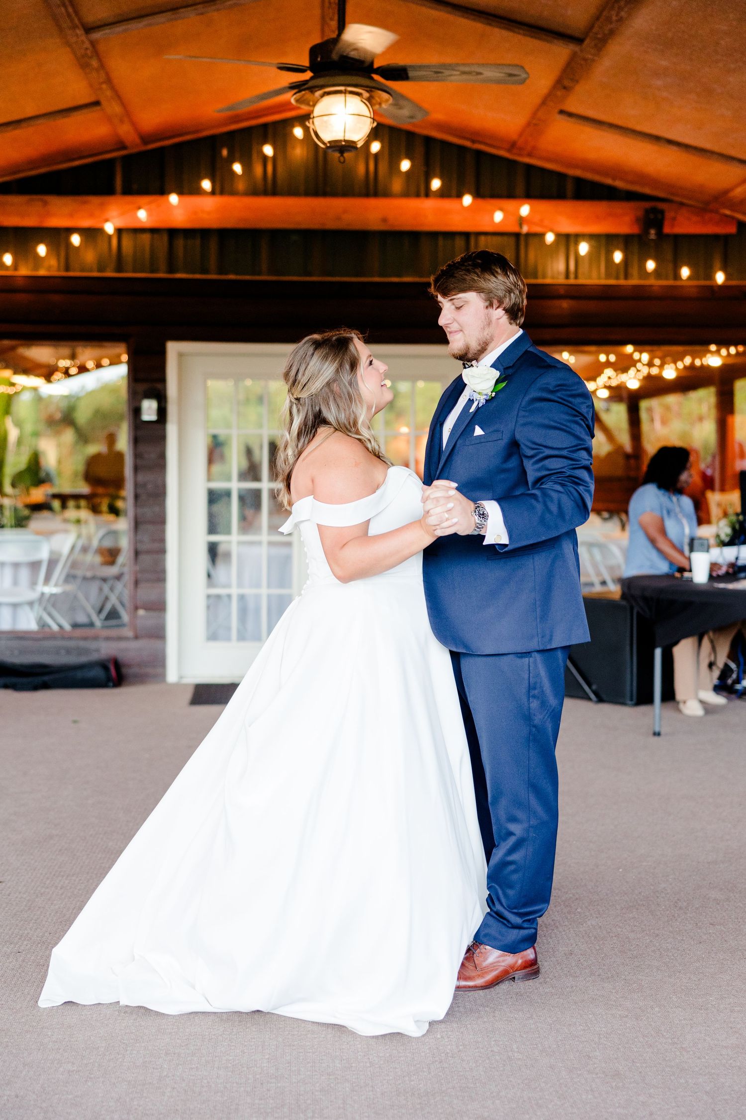 A dancing couple twirls across a reception floor, with the bride's white dress flowing elegantly.
