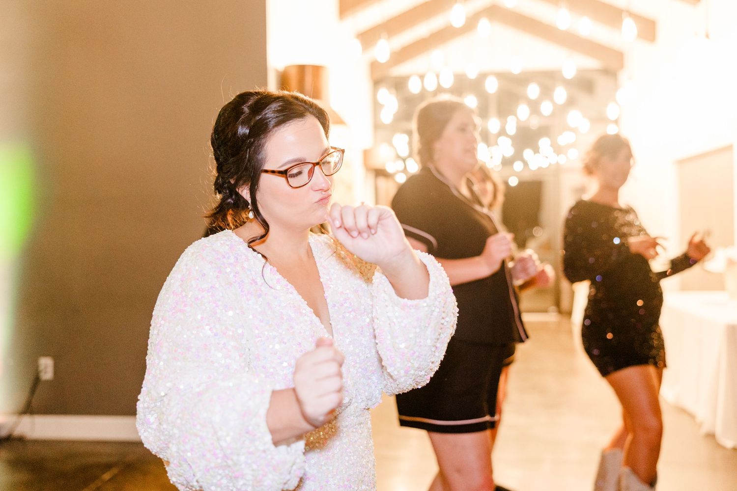 Wedding reception dance floor filled with guests celebrating under warm lighting.
