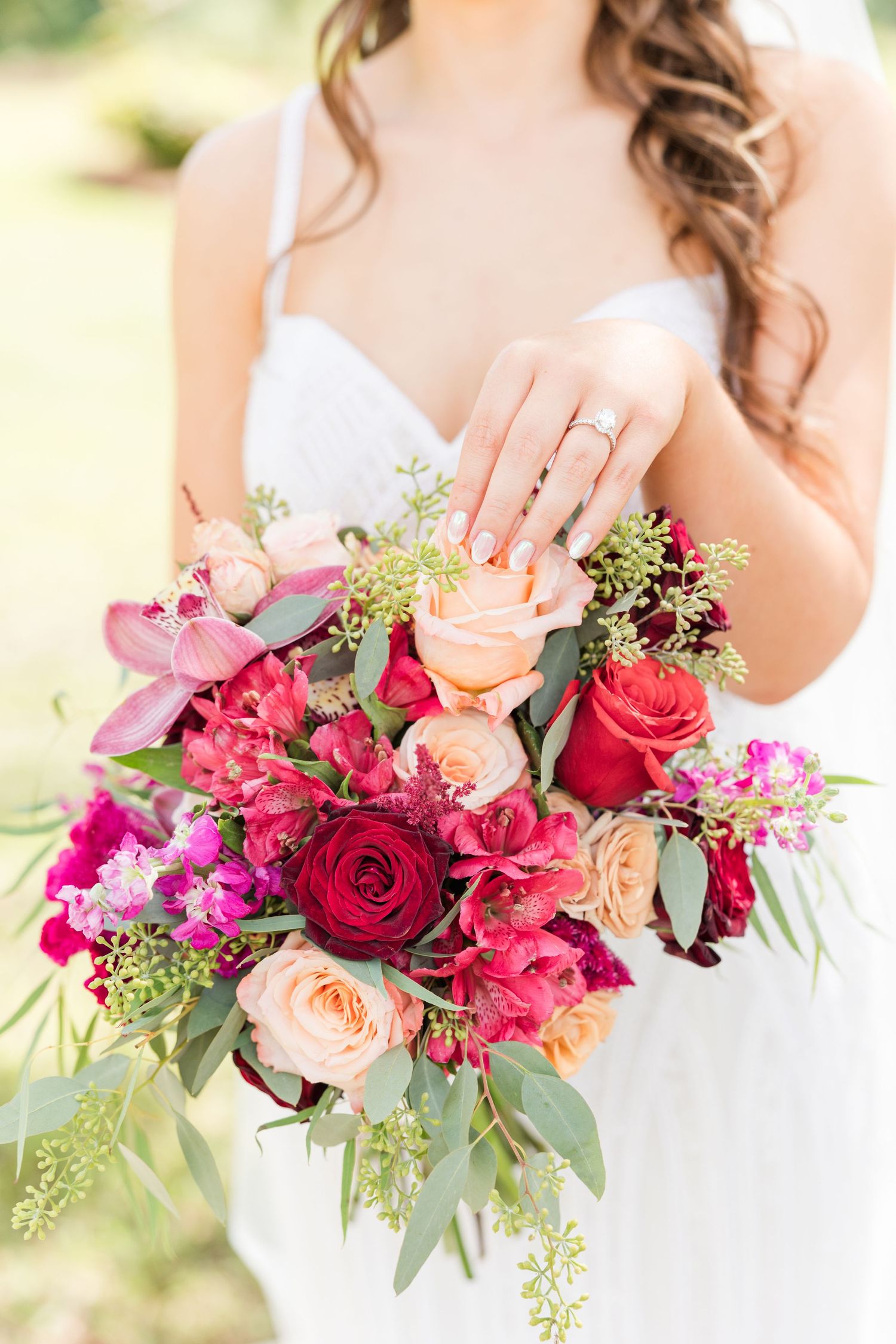 Row of stunning wedding bouquets featuring pink roses, red blooms and eucalyptus greenery.