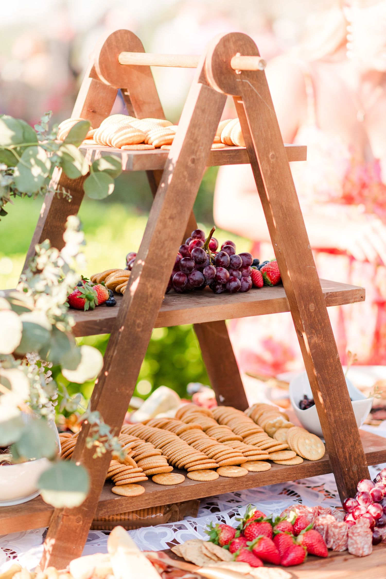 Rustic wooden display stand with cookies, berries and floral decorations at wedding reception.