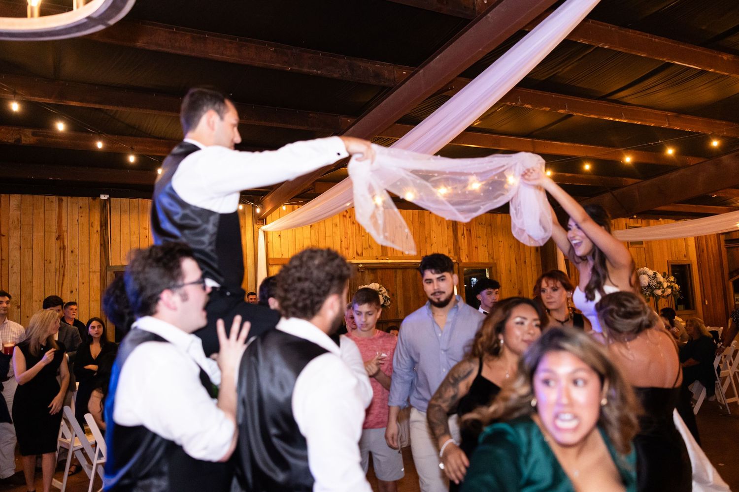 Celebration with guests waving fabric streamers at wedding reception.