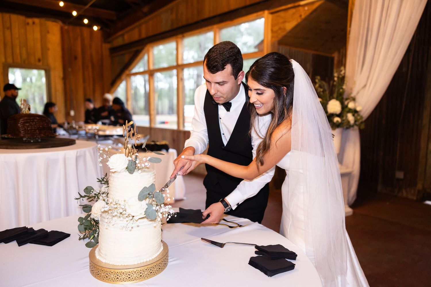 Wedding couple cuts their white and gold wedding cake together at the reception.