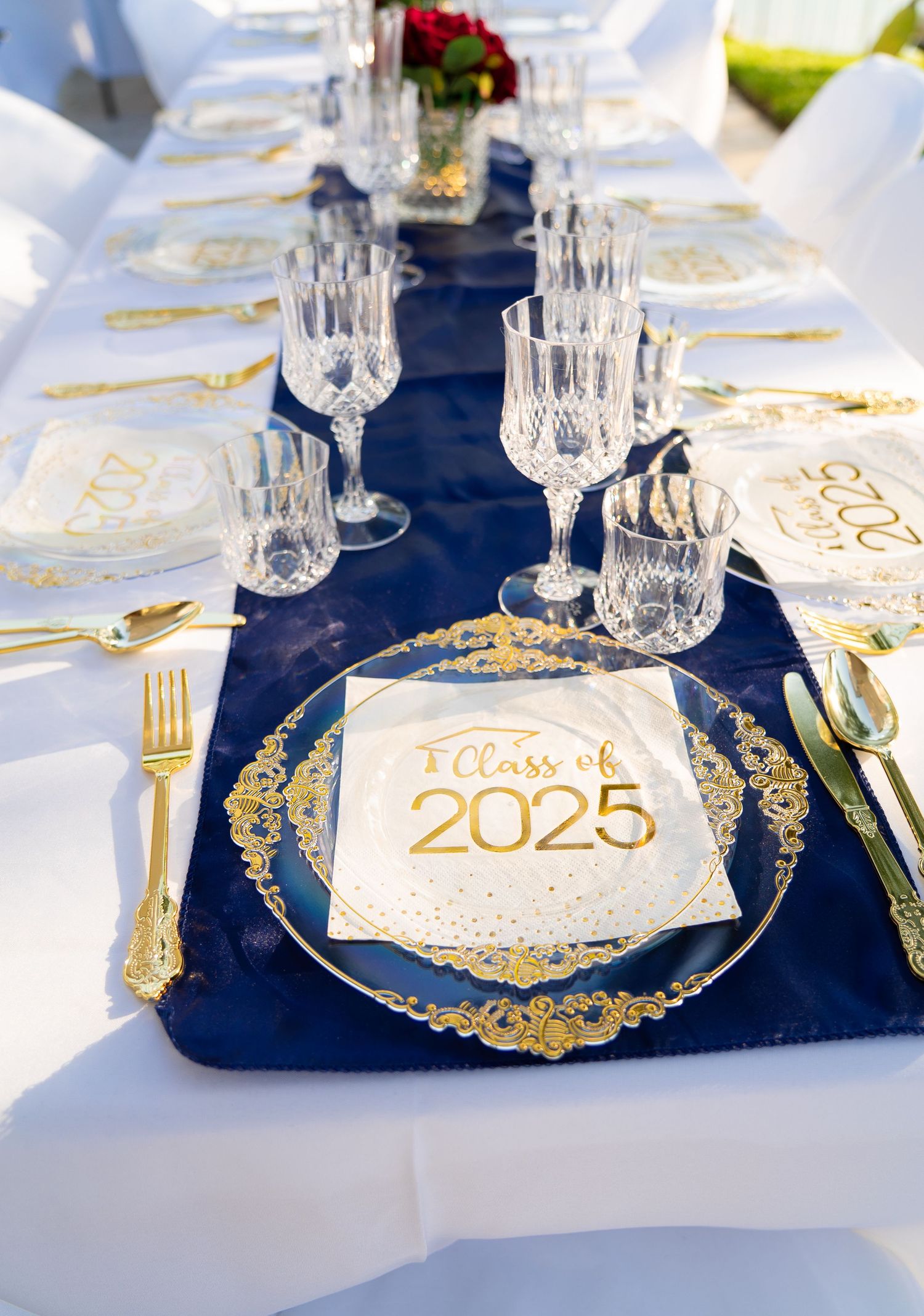Class of 2025 graduation party table setting with navy blue runner and gold accented dinnerware.