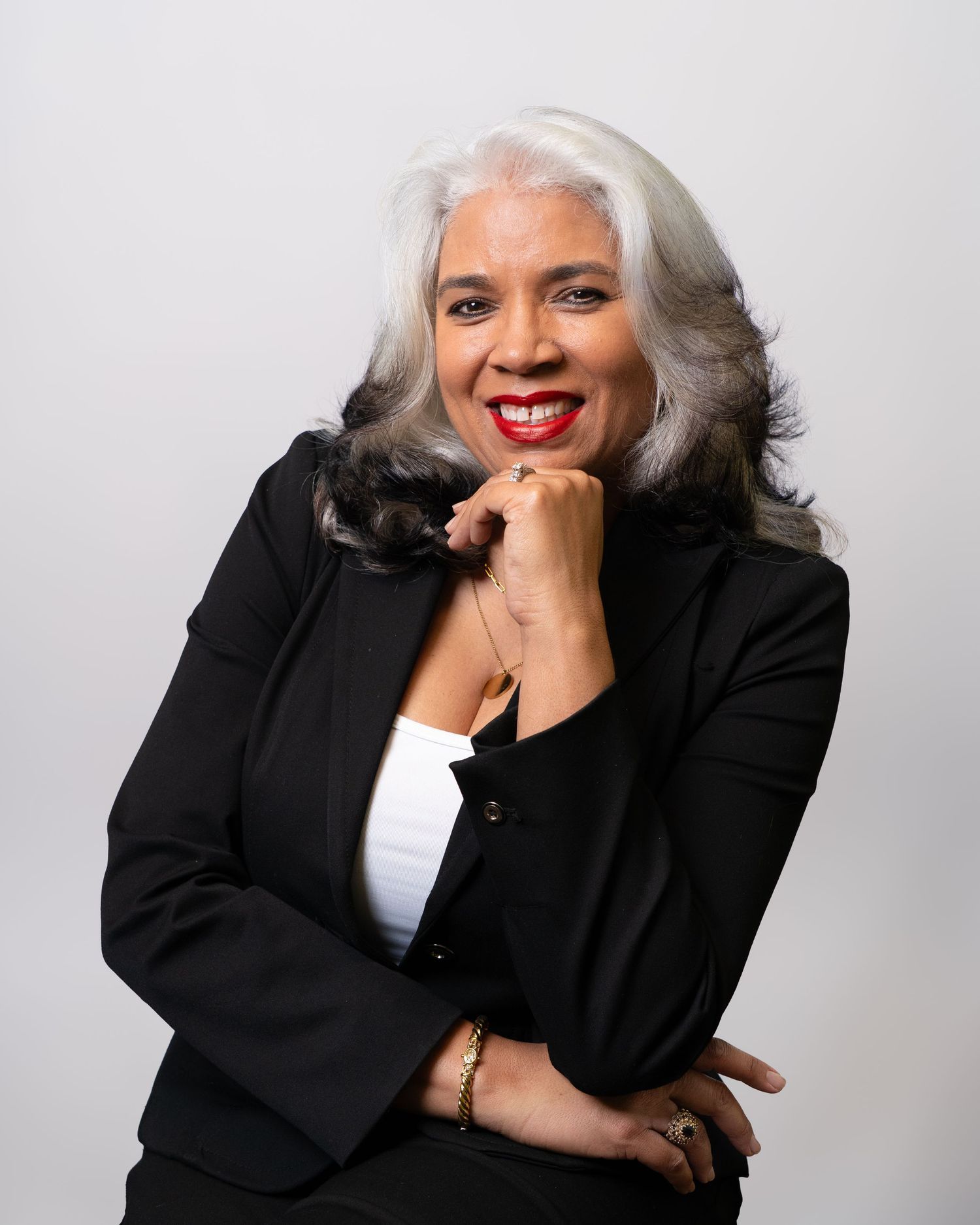 Confident woman with silver hair in black blazer posing for professional headshot.