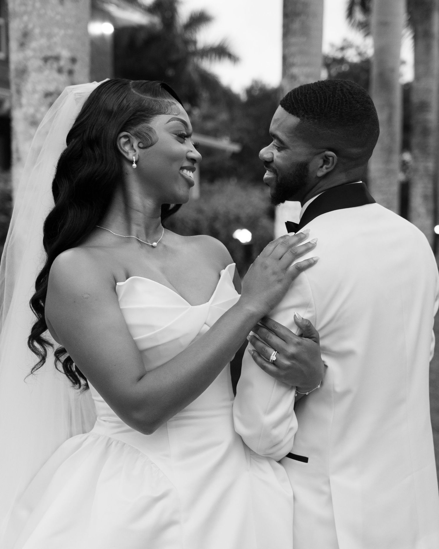 Black and white wedding photo of bride and groom sharing romantic moment in formal attire.