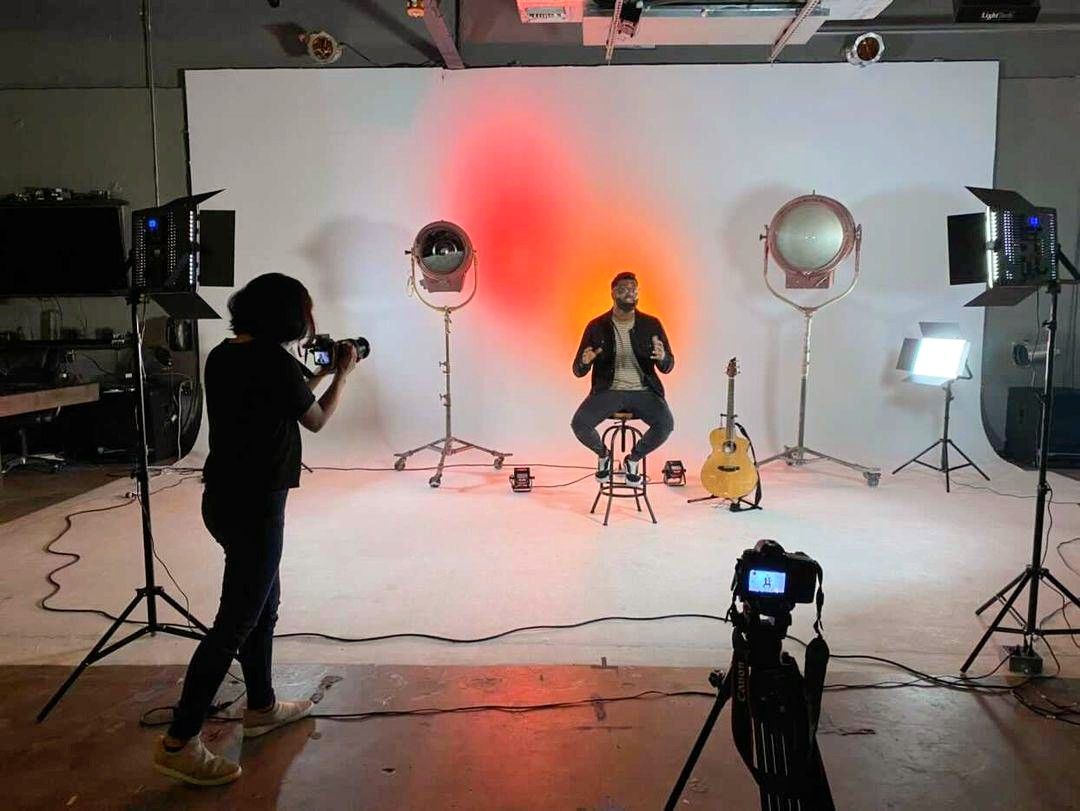 Yshia Condezo filming an interview for a client in a professional studio with colorful lighting.