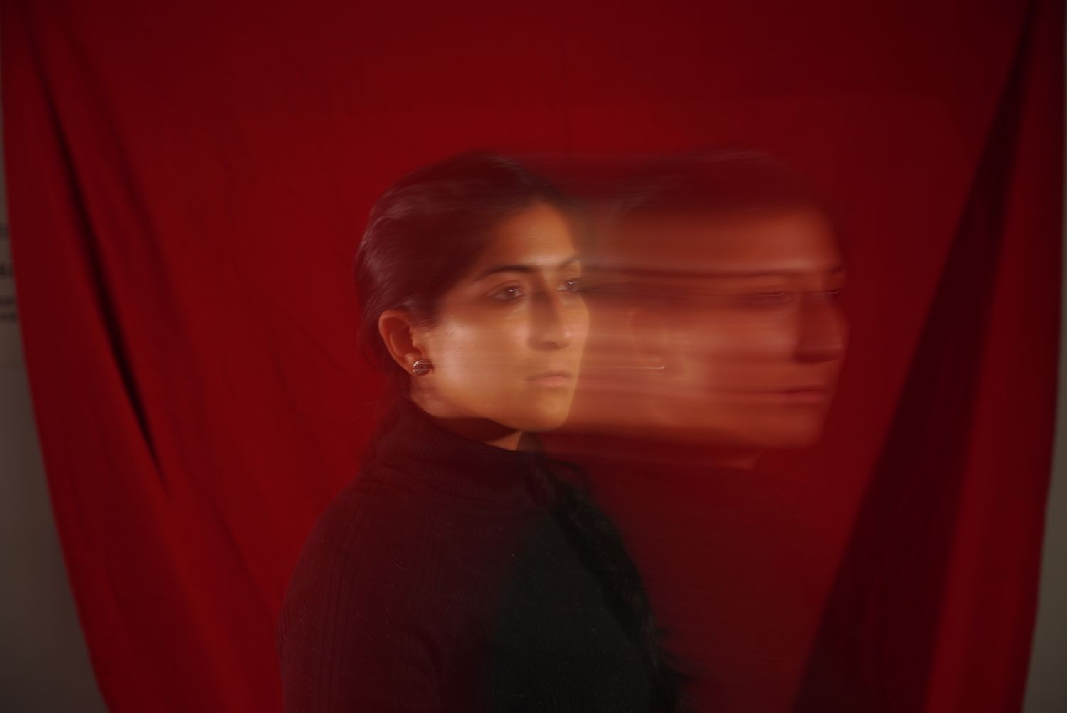 Artistic motion blur portrait of Yshia Condezo against a red backdrop.