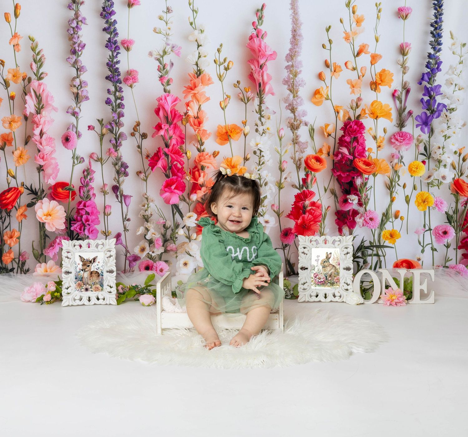 Baby during One Wild Flower-themed cake smash in Chicago IL studio with colorful floral backdrop, greenery, and playful wildflower decor.
