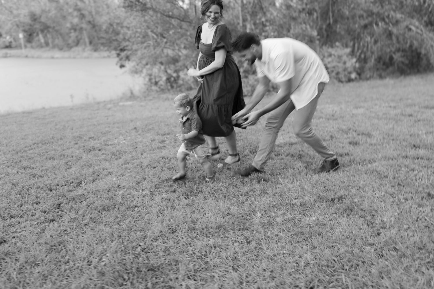 joyful maternity family session at Urfer Park in Sarasota, FL, with the expecting mother, husband, and child surrounded by lush greenery