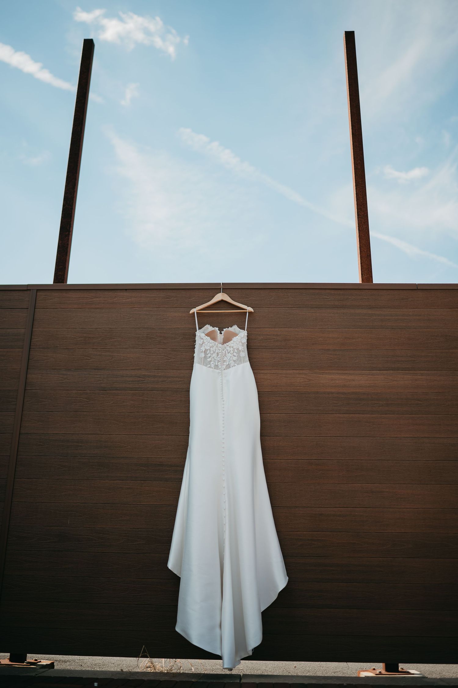 A white wedding dress hangs against a wooden wall under a blue sky in a sequence of minimalist photographs.