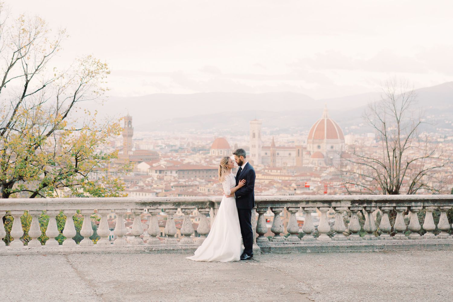 newlyweds hugging each other in Piazzale Michelangelo, with the dome of Florence in the background