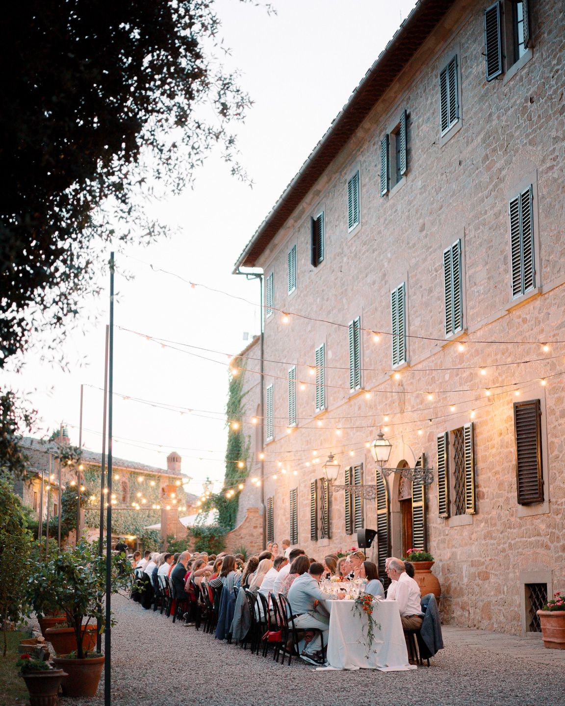 wedding guests sitting outdoor at a dinner table under the lights at Borgo Castelvecchi