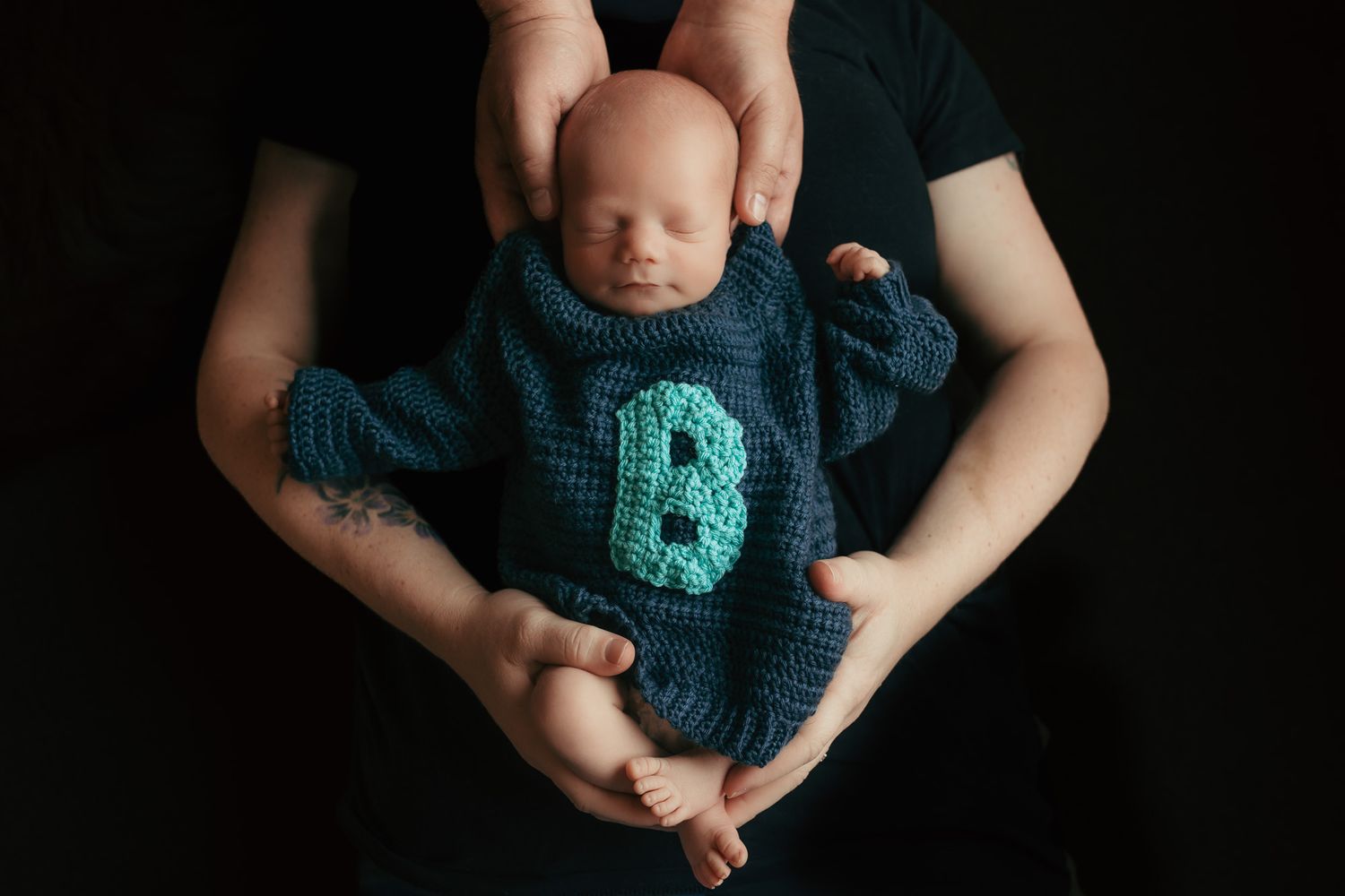 Newborn baby sleeping in parents’ arms during a lifestyle newborn photography session in Wausau, Wisconsin