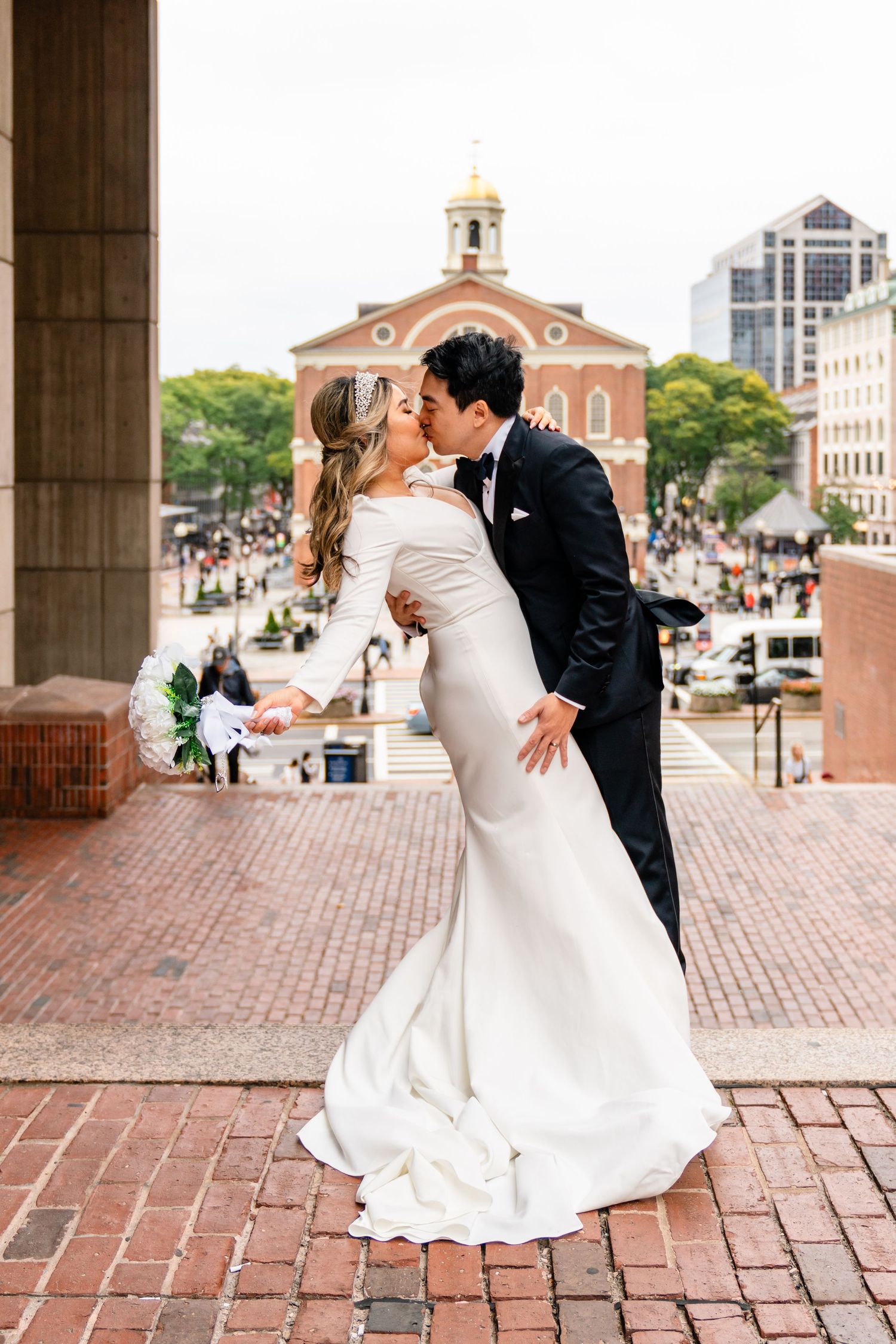 Elegant wedding portrait on brick plaza with historic Boston architecture in background.