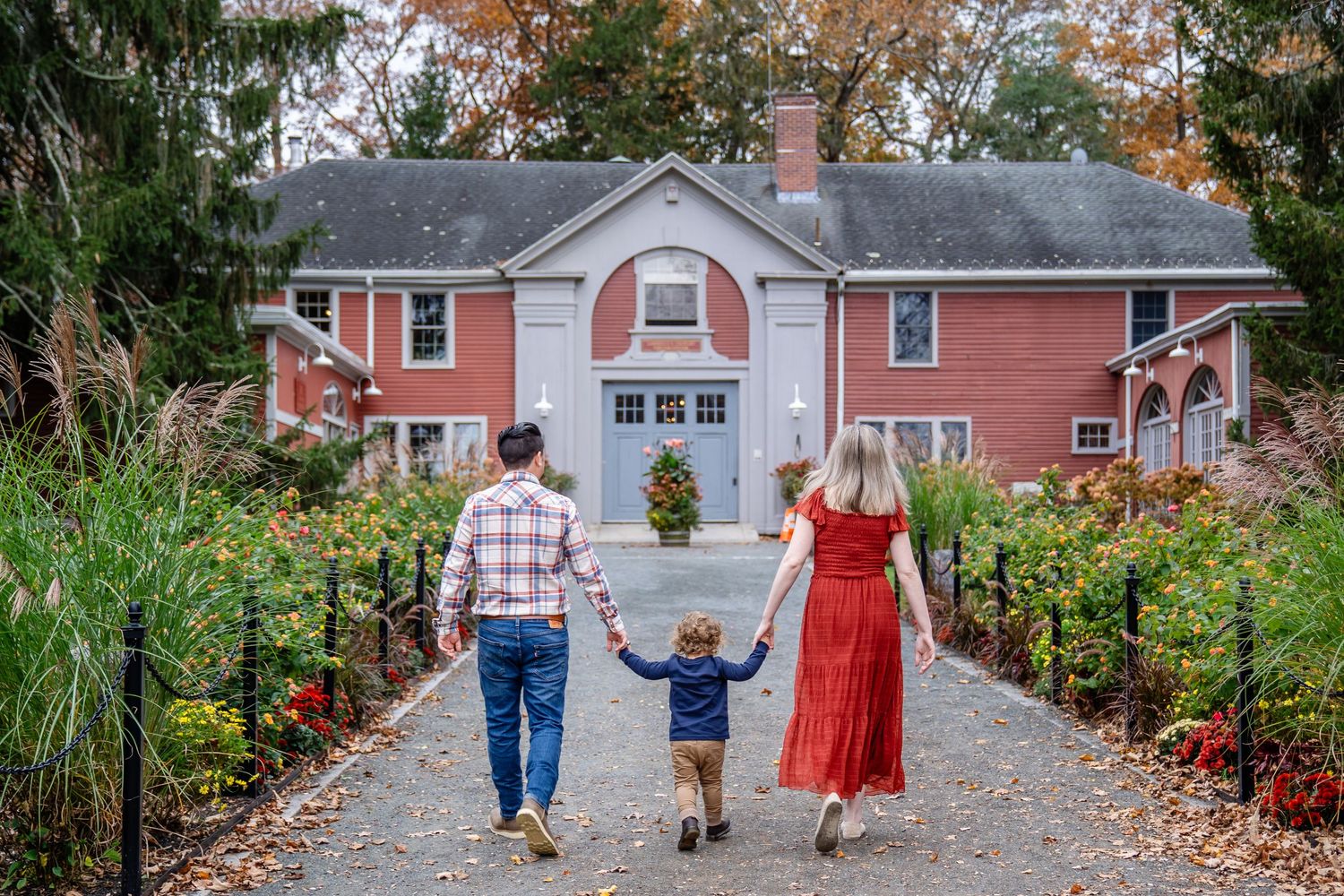 A tender family moment captured on a leaf-covered path during autumn with colorful foliage surrounding them.