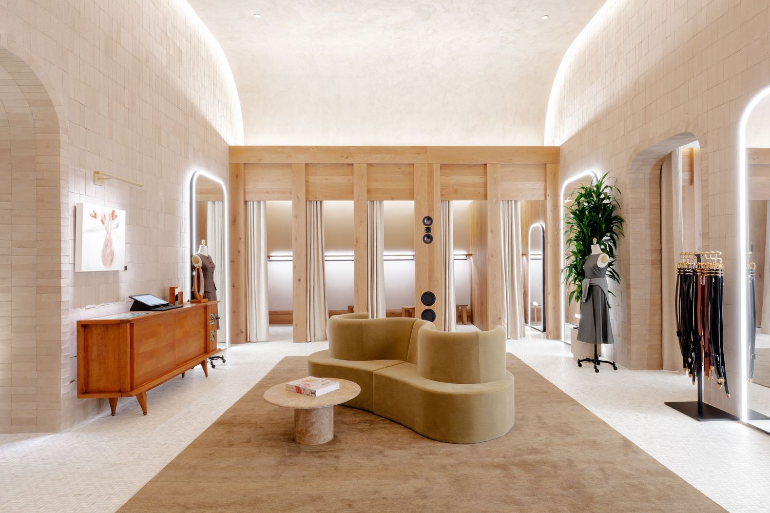 Elegant luxury boutique interior with arched mirrors, velvet sofa, and neutral stone-textured walls.