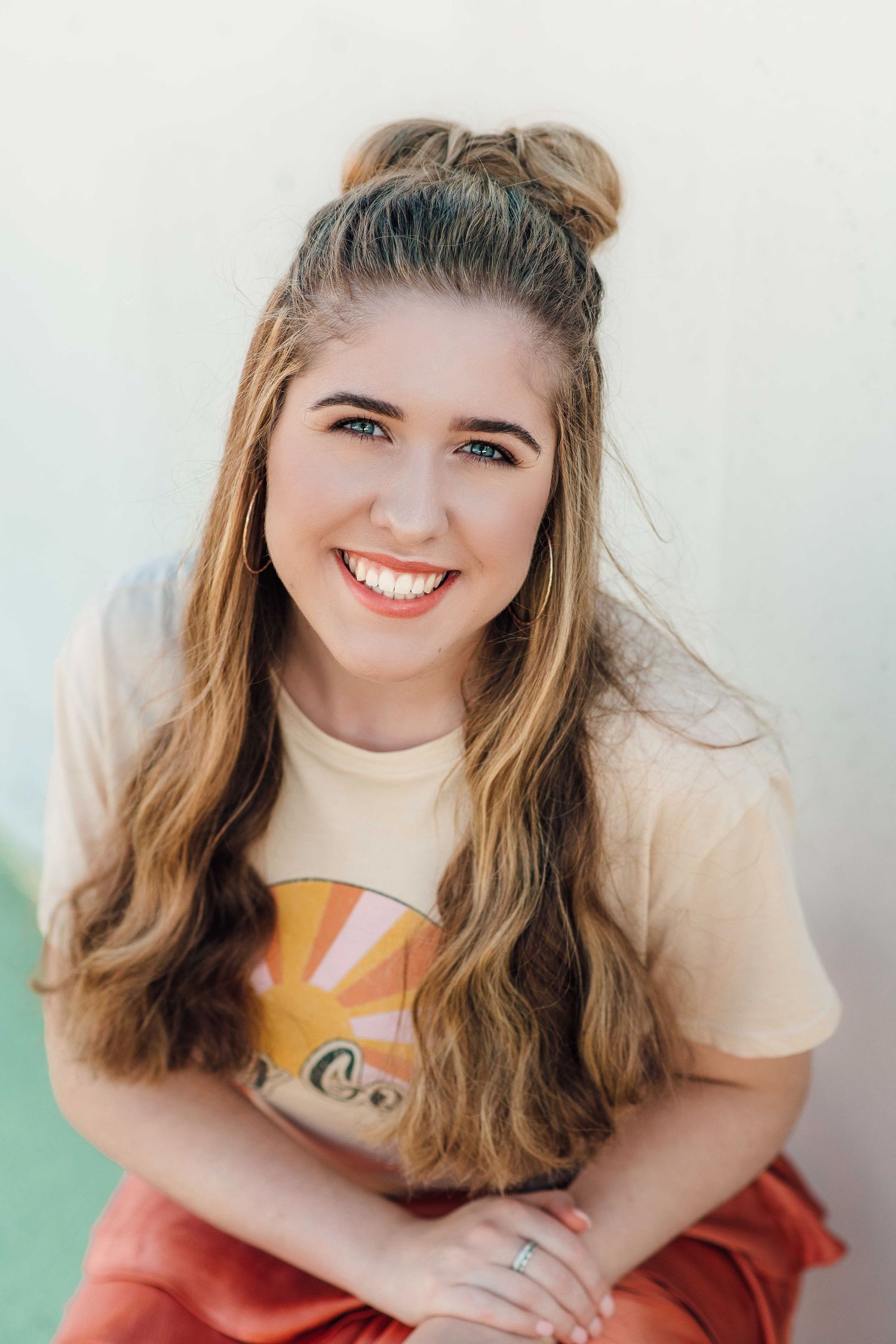 Happy young woman with a half-up bun hairstyle wearing a vintage graphic tee, smiling outdoors.