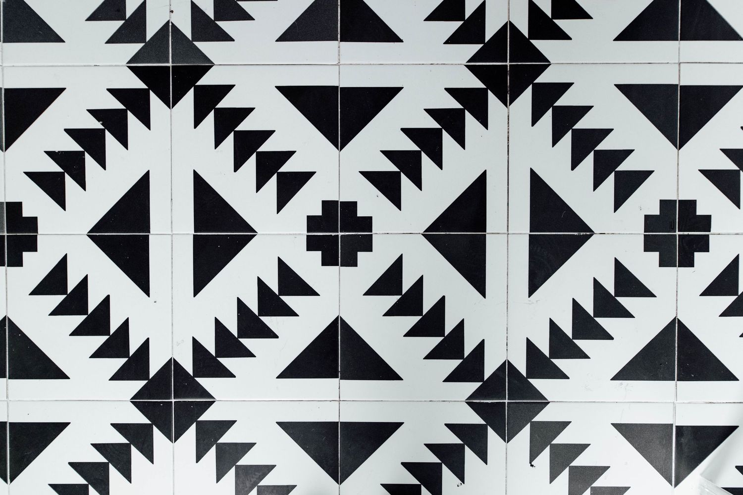 Black and white geometric patterned tiles featuring triangles and diamond shapes in a repeating symmetrical design.