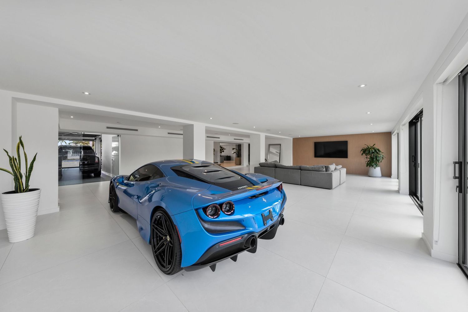 A bright blue sports car parked inside a modern white interior space.