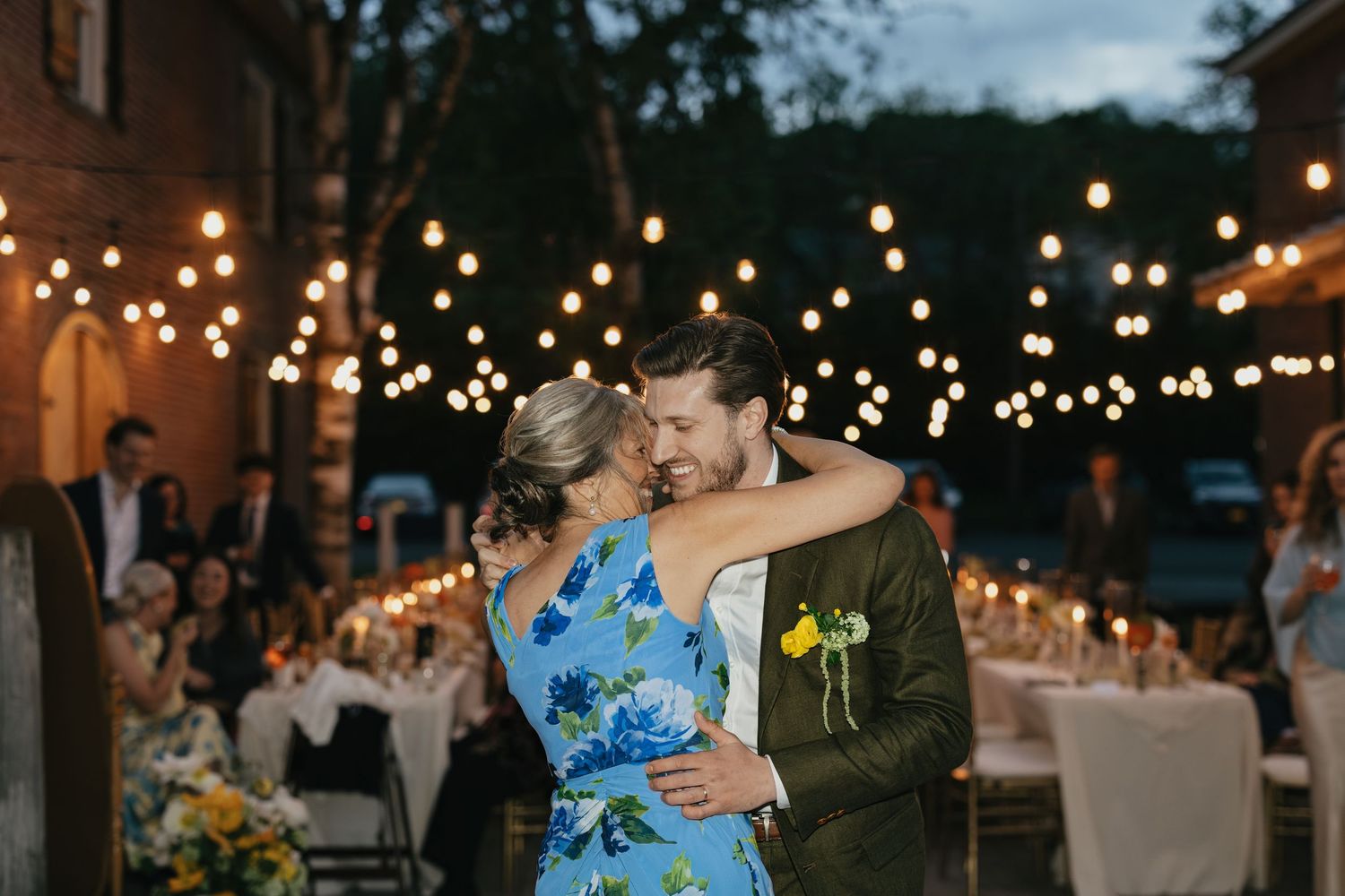 Evening outdoor wedding celebration with string lights illuminating dancers on the patio.