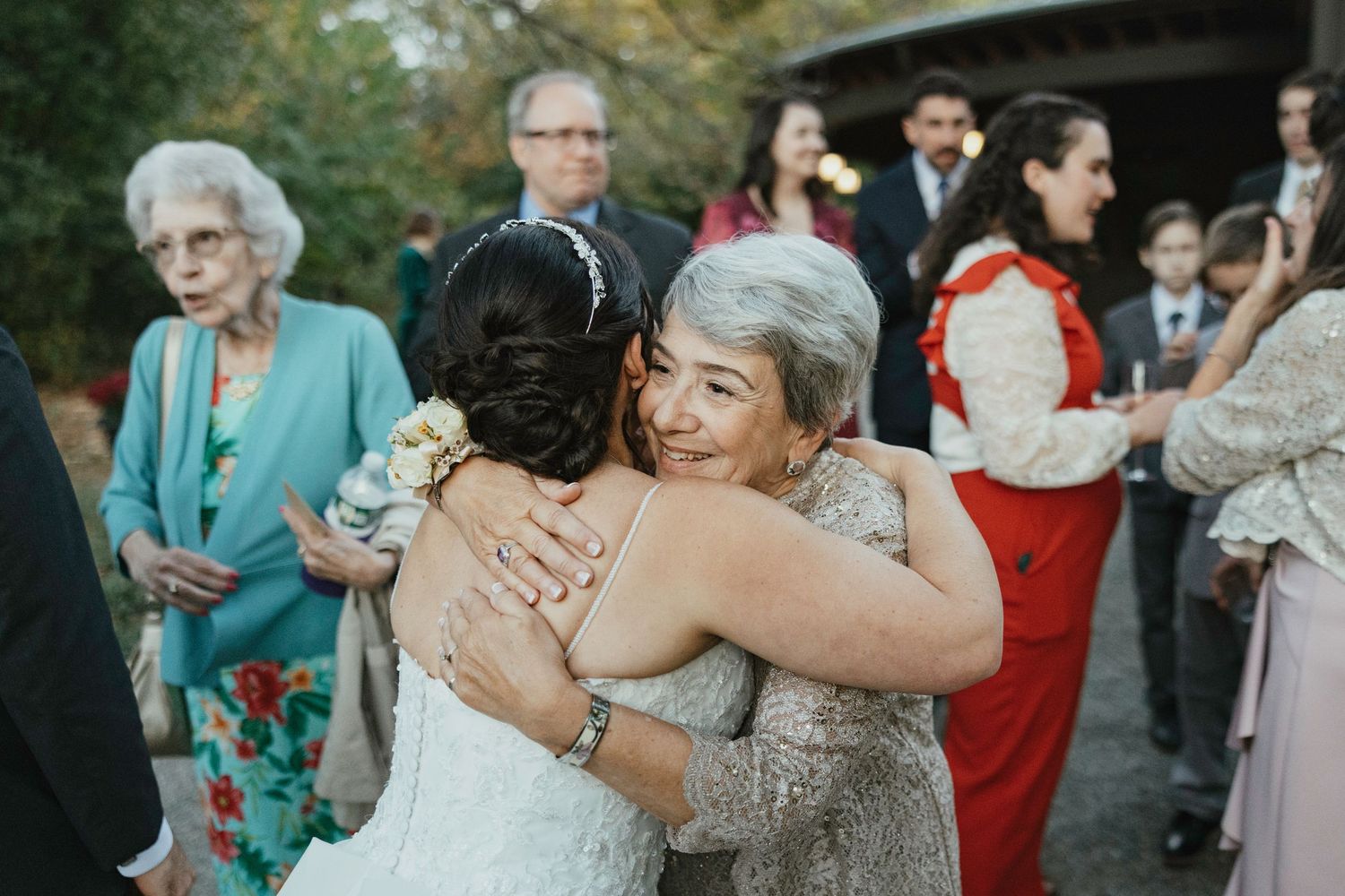 Wedding guests sharing emotional embraces and hugs during outdoor celebration.