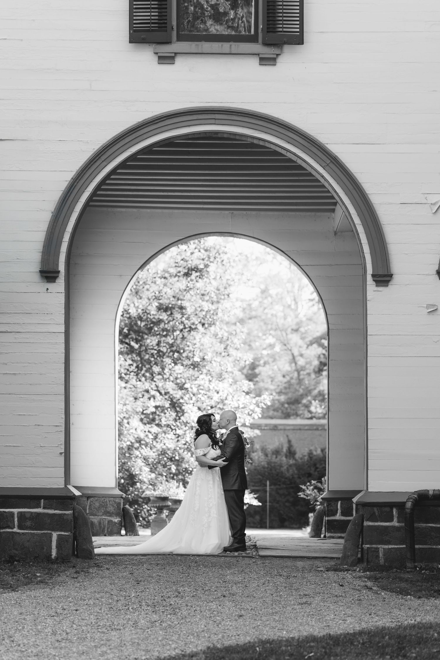 A series of black and white photos showing a couple in formal attire posing under an elegant archway at different angles.