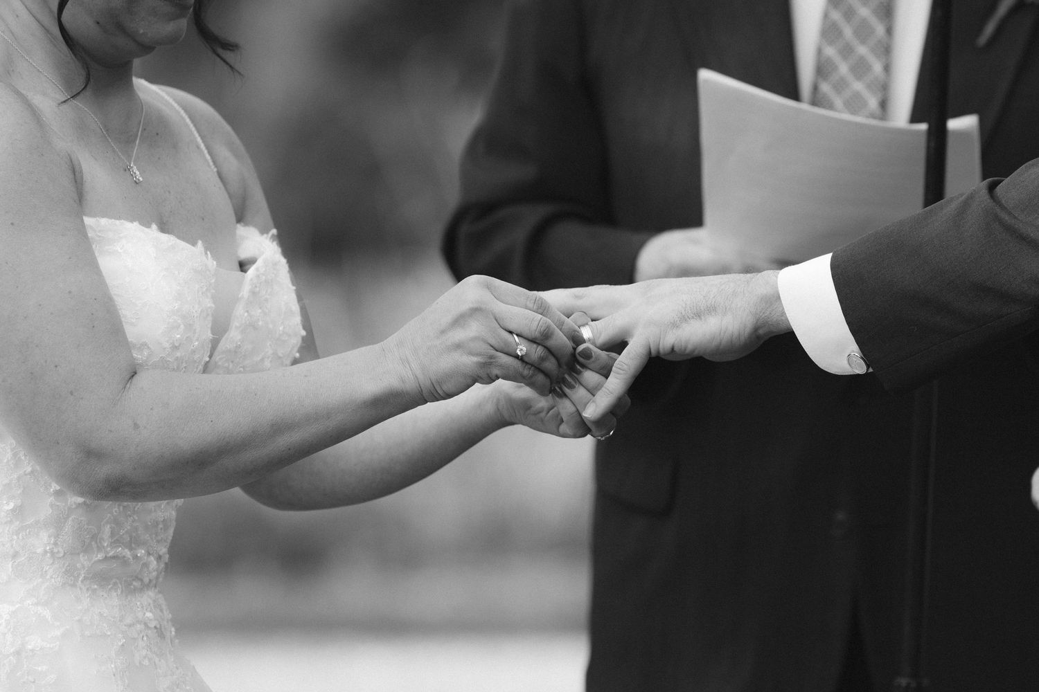 Close-up of hands exchanging wedding rings during a marriage ceremony.