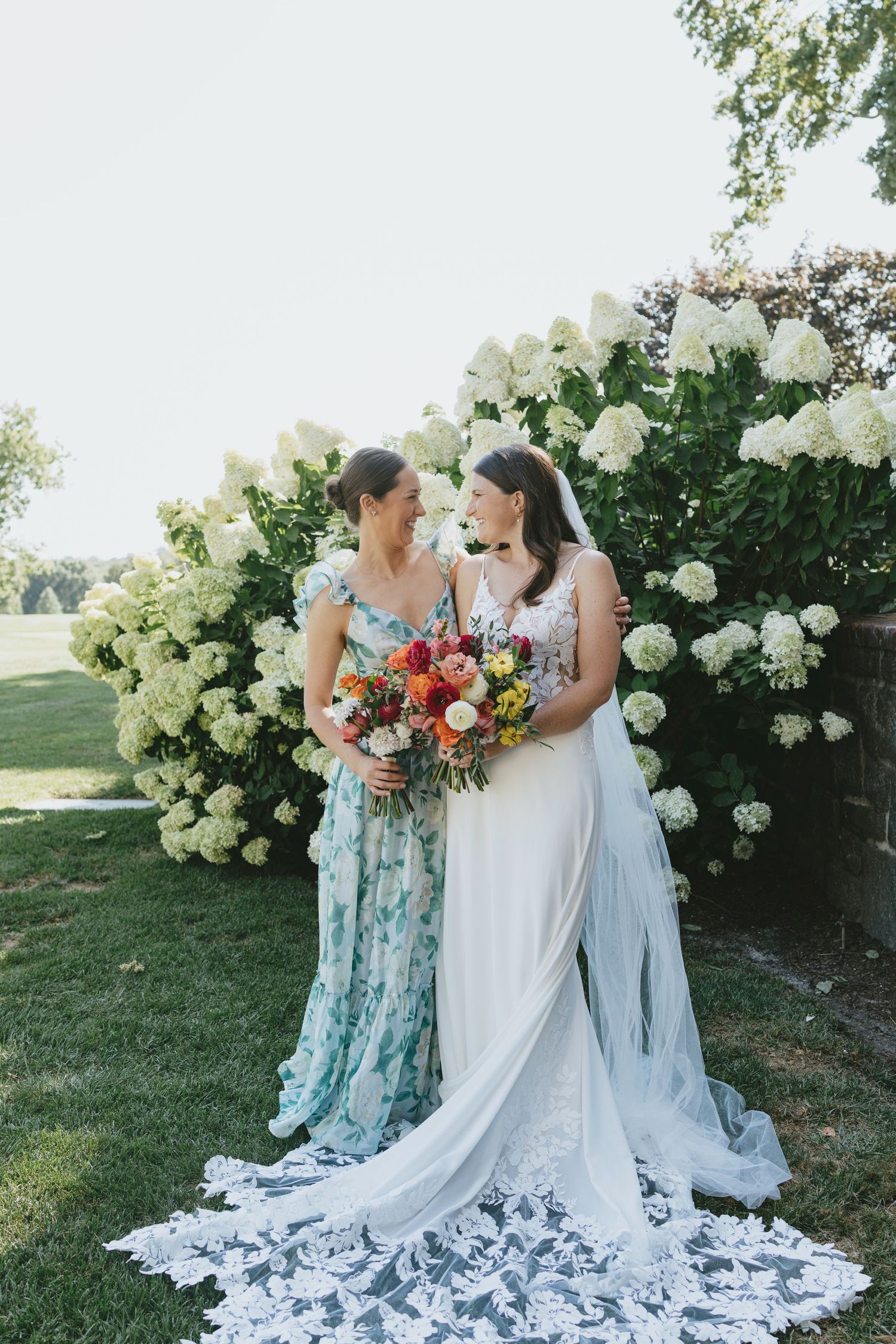 A wedding scene with floral arrangements featuring white hydrangeas and orange bouquets in an outdoor garden setting.