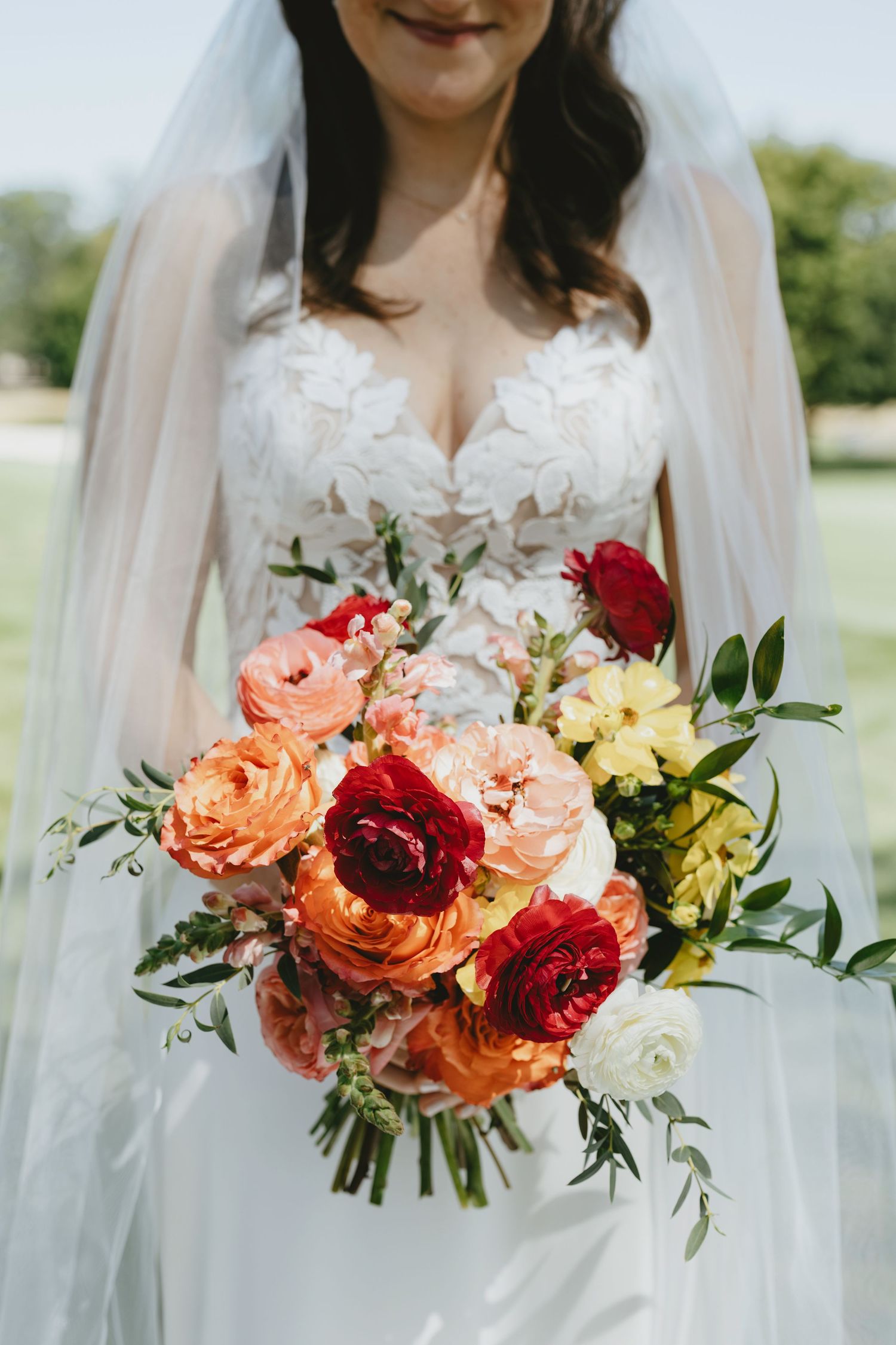 Beautiful wedding bouquets featuring coral, red and white roses with delicate greenery against a light background.