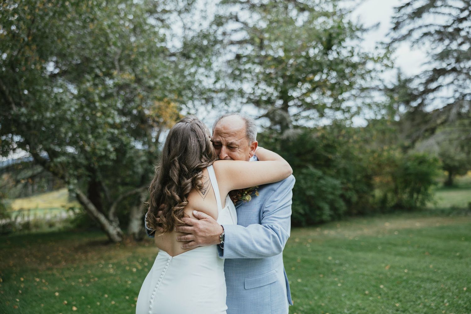 Two people share a tender embrace outdoors in a scenic garden setting during a special celebration.