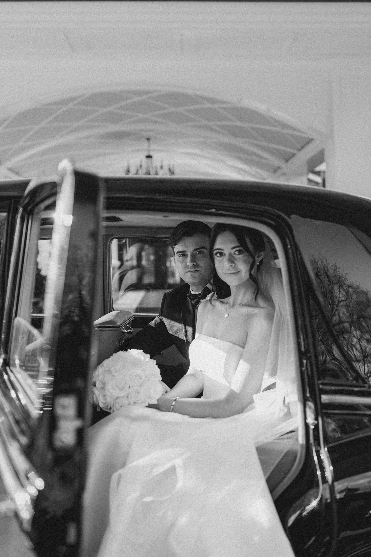 A sequence of black and white photos showing a bride in a wedding dress sitting in the backseat of a vintage car.