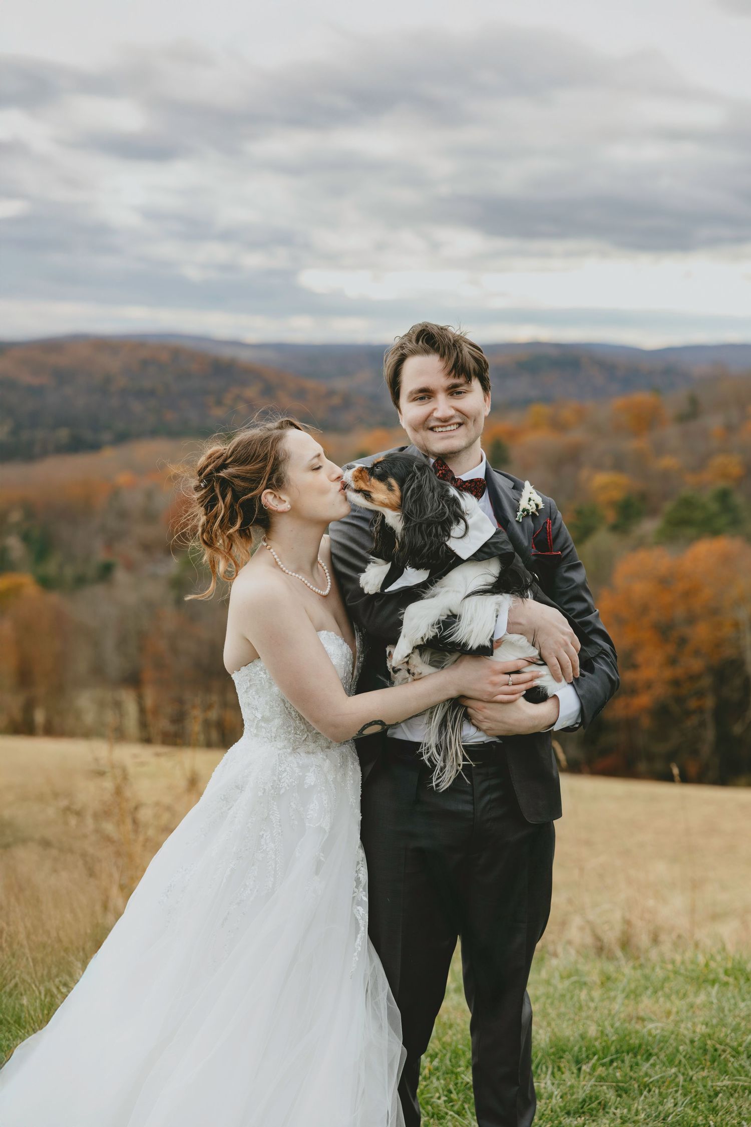 Wedding couple sharing playful moments in an autumn field with mountains in the background.