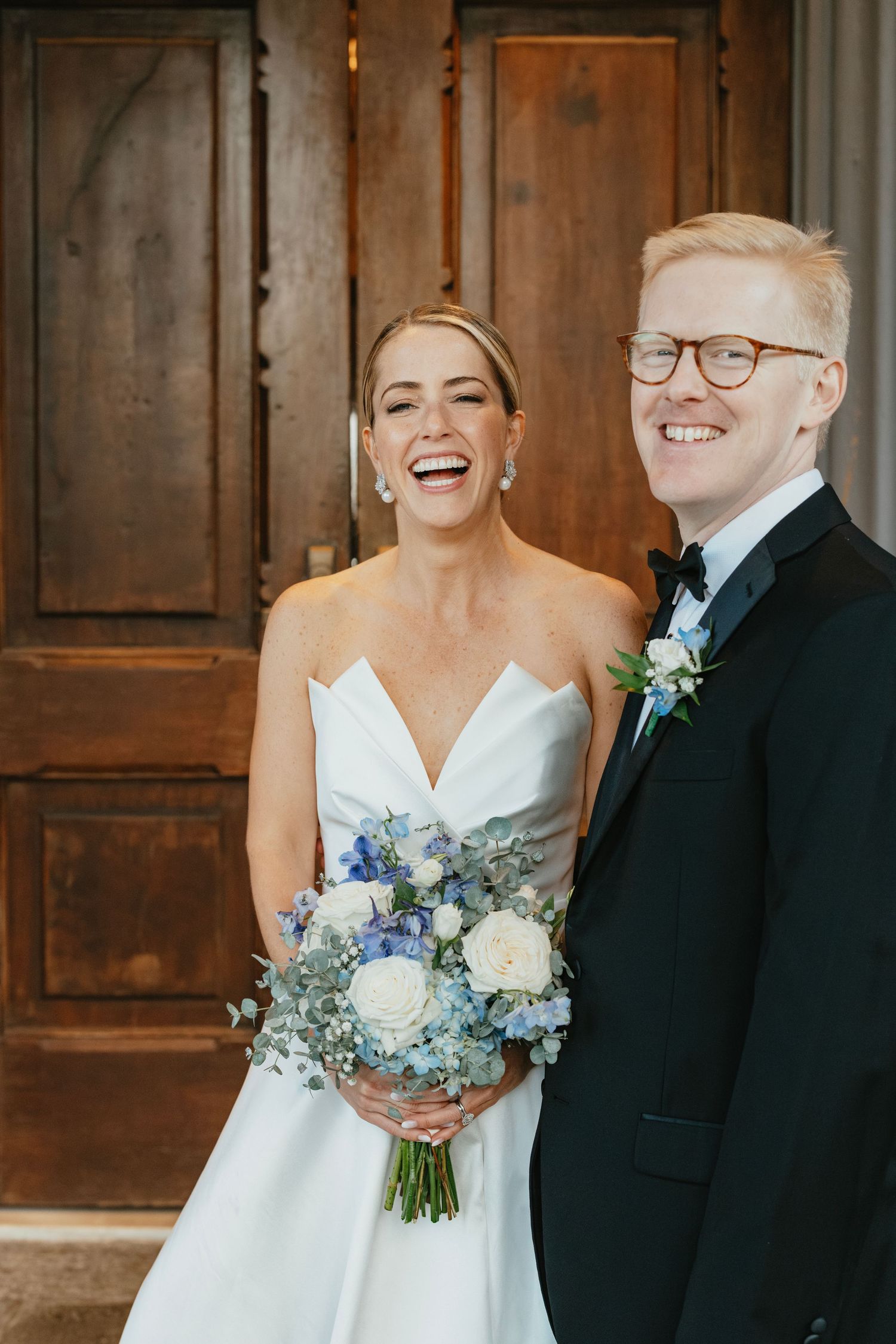A happy couple shares joyful moments during their wedding, with the bride holding a blue and white floral bouquet.