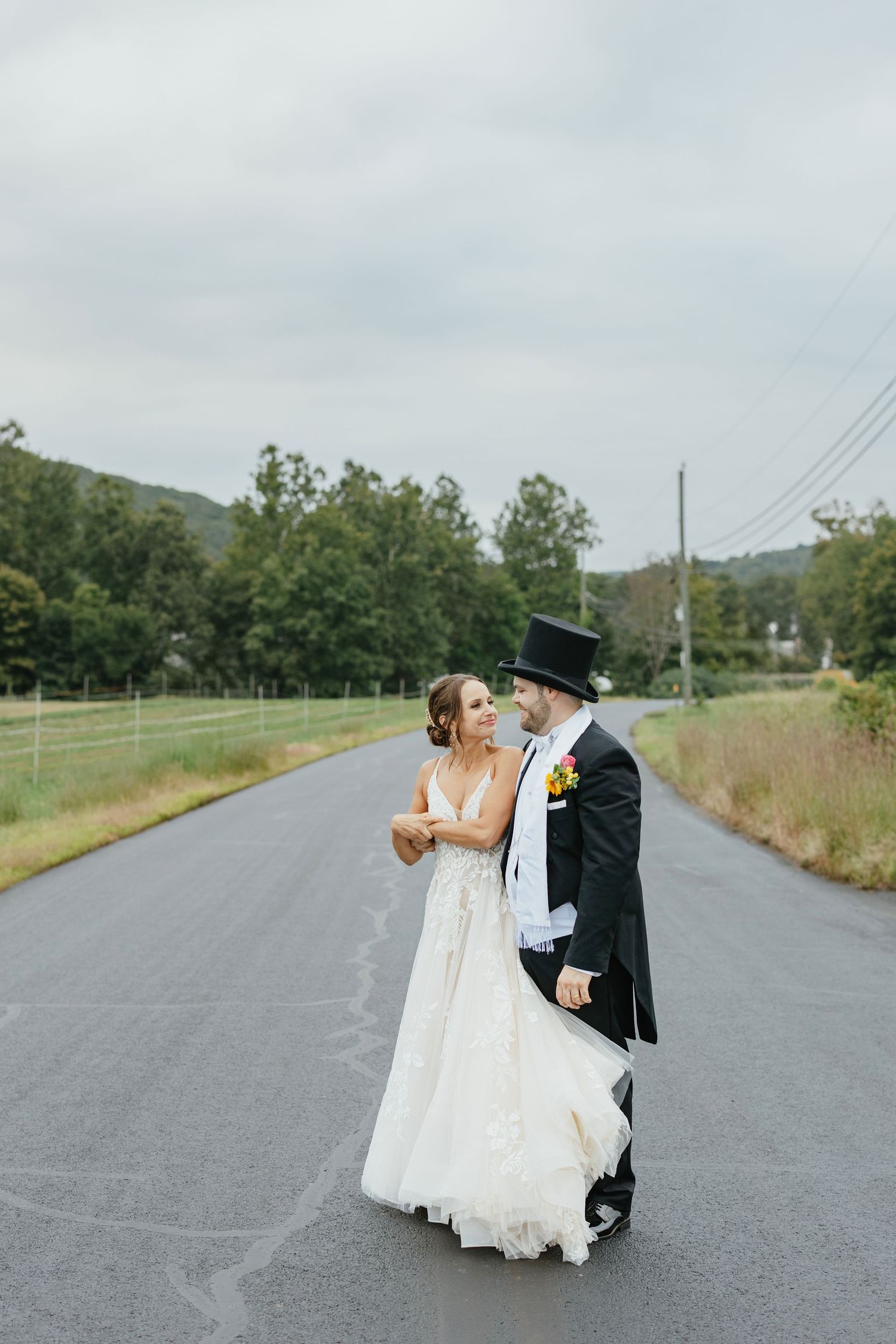 A romantic wedding couple shares a kiss on a quiet country road in a series of black and white photos.