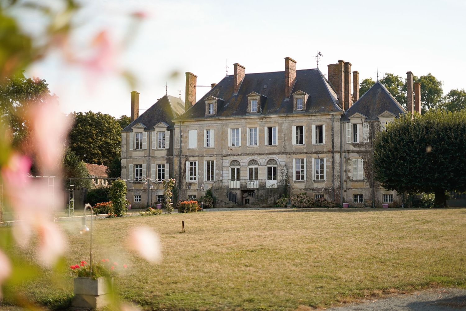 A majestic French chateau with classic architecture stands proudly against a summer sky.