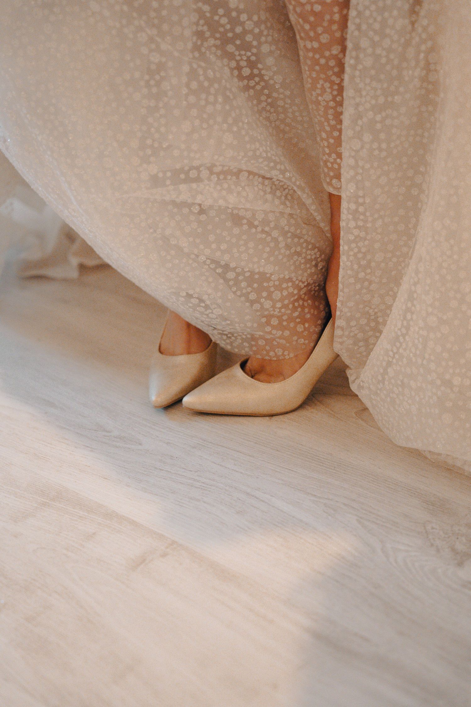 White curtain and sheer fabric softly draping over a light-colored hardwood floor in a minimalist room.