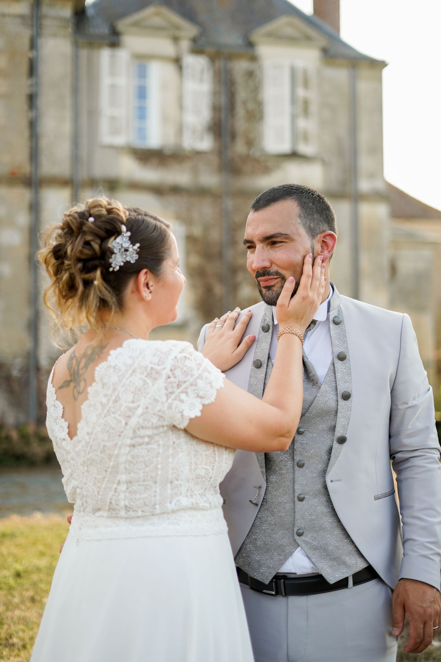 A tender moment between newlyweds sharing an intimate gesture in front of a historic chateau.